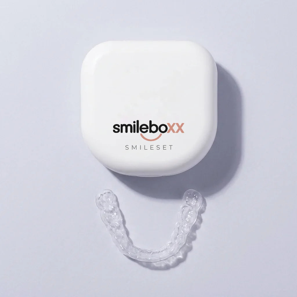 A white aligner case printed smileboxx and SMILESET above a clear aligner tray