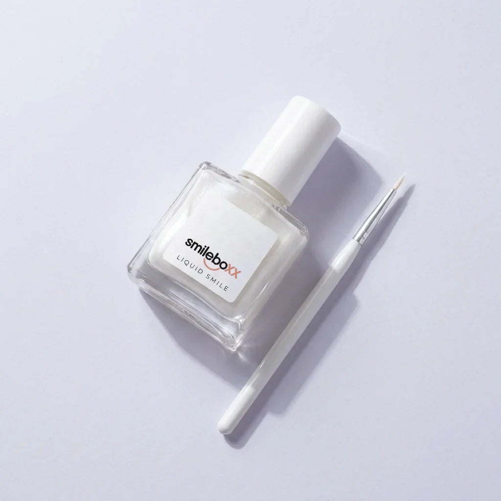A glass bottle labeled smileboxx LIQUID SMILE beside a fine brush