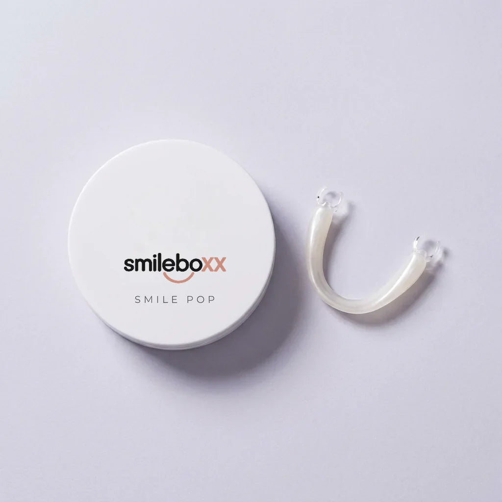 A round white case printed smileboxx and SMILE POP beside a slim pearl-white arc
