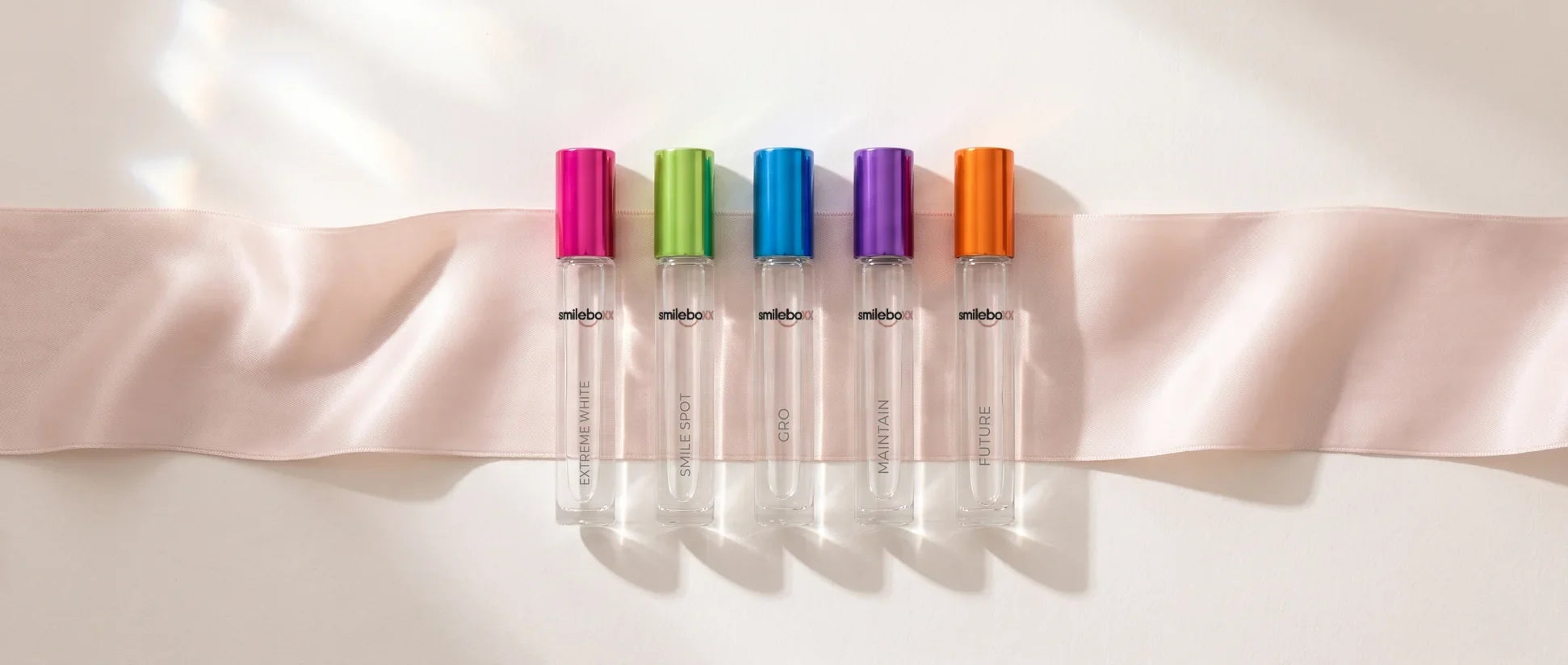 Five Smile BOXX glass ampoules lying side by side on blush silk